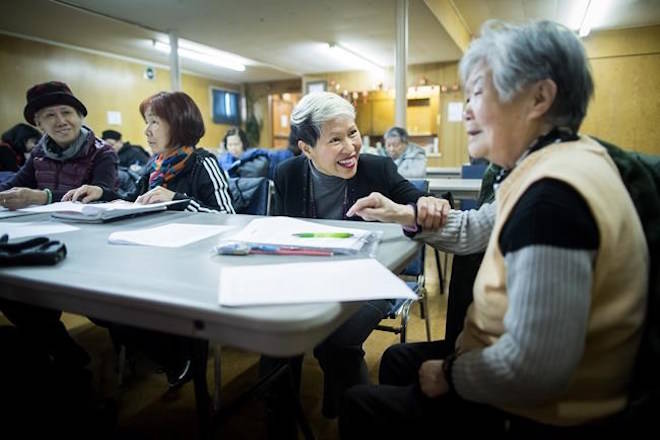 Amie Peacock, centre, founder of the volunteer group Beyond the Conversation, speaks with a senior citizen during a weekly group meeting to help people practice their English skills, combat social isolation and foster relationships, in Vancouver. (Darryl Dyck/The Canadian Press)