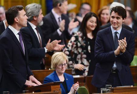 Finance Minister Bill Morneau, left, receives an ovation after delivering the federal budget in the House of Commons in Ottawa on Tuesday. (Sean Kilpatrick/The Canadian Press)