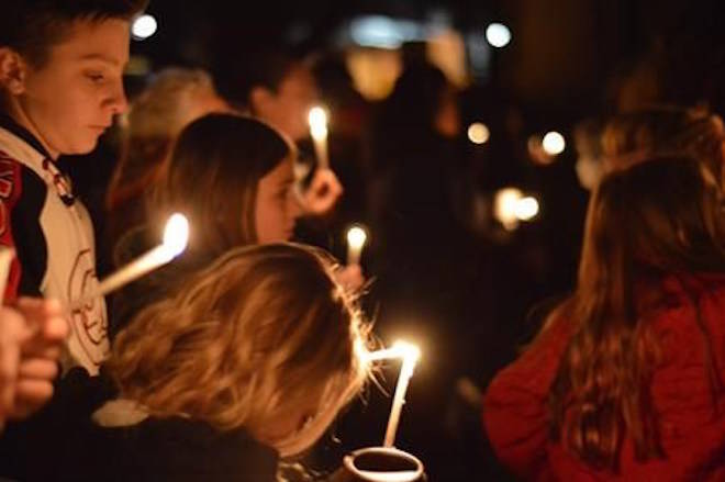 FILE - In this Dec. 7, 2017, file photo, Aztec High School students and area residents gather for a candlelight vigil in Aztec, N.M., after a shooting at the high school. While students across the country plan walkouts to protest gun violence, teens at the New Mexico high school still reeling after two classmates were gunned down in December by an armed intruder have organized a “walk-up” to help unify a campus with varied ideas on school safety. (AP Photo/Russell Contreras, File)
