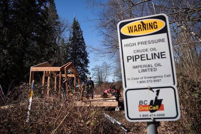 A sign warms of an underground pipeline as people construct a “watch house” near a gate leading to Kinder Morgan’s property during a protest against the company’s Trans Mountain pipeline expansion in Burnaby, B.C., on Saturday March 10, 2018. Protesters must be restrained from obstructing the expansion of the Trans Mountain pipeline, says a British Columbia Supreme Court judge who has granted the company an injunction aimed at preventing people from entering within five metres of two work sites. THE CANADIAN PRESS/Darryl Dyck
