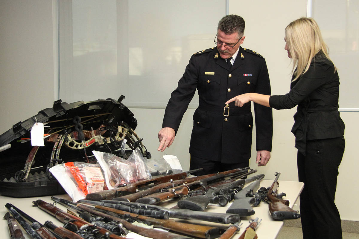 GUN BUST - Red Deer RCMP Superintendent Ken Foster and Mayor Tara Veer looked over the 29 firearms recently seized from two search warrants. Two individuals have been charged with 198 criminal charges. Todd Colin Vaughan/Red Deer Express