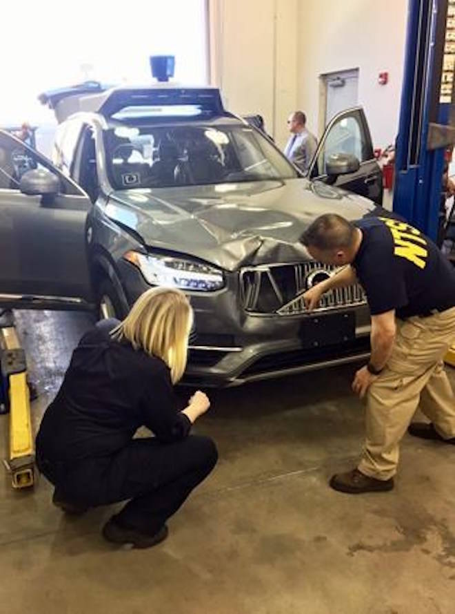 In this March 20, 2018, photo provided by the National Transportation Safety Board, investigators examine a driverless Uber SUV that fatally struck a woman in Tempe, Ariz. The fatality prompted Uber to suspend all road-testing of such autos in the Phoenix area, Pittsburgh, San Francisco and Toronto. (National Transportation Safety Board via AP)