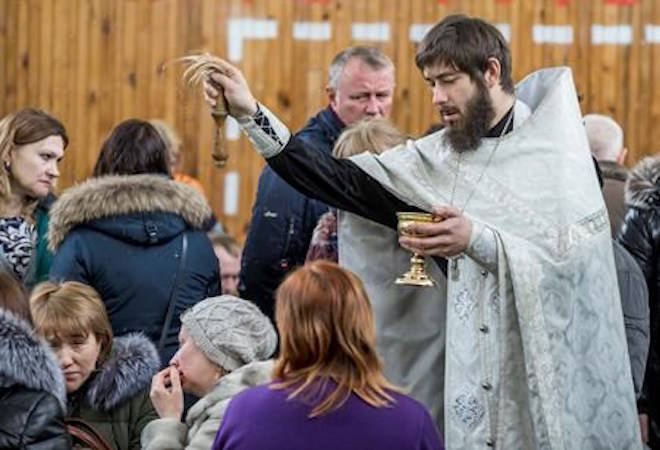 A Russian Orthodox priest conducts a requiem for the victims of a fire in a multi-story shopping center in the Siberian city of Kemerovo, about 3,000 kilometers (1,900 miles) east of Moscow, Russia, Monday, March 26, 2018. Russia’s top investigative body says over 50 people are confirmed dead in a fire at a shopping mall in Siberia. The fire at the four-story Winter Cherry mall in the Siberian city of Kemerovo was extinguished by Monday morning after burning through the night. (AP Photo)