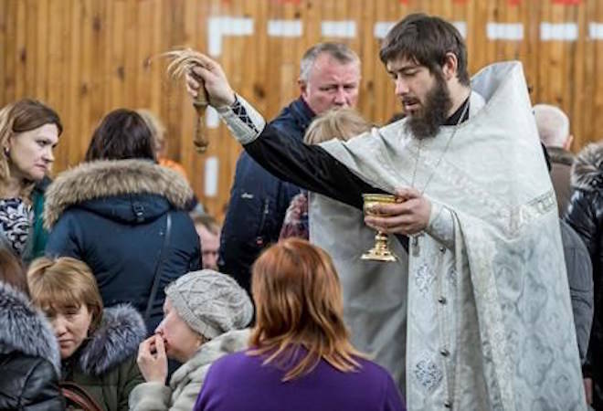 A Russian Orthodox priest conducts a requiem for the victims of a fire in a multi-story shopping center in the Siberian city of Kemerovo, about 3,000 kilometers (1,900 miles) east of Moscow, Russia, Monday, March 26, 2018. Russia’s top investigative body says over 50 people are confirmed dead in a fire at a shopping mall in Siberia. The fire at the four-story Winter Cherry mall in the Siberian city of Kemerovo was extinguished by Monday morning after burning through the night. (AP Photo)