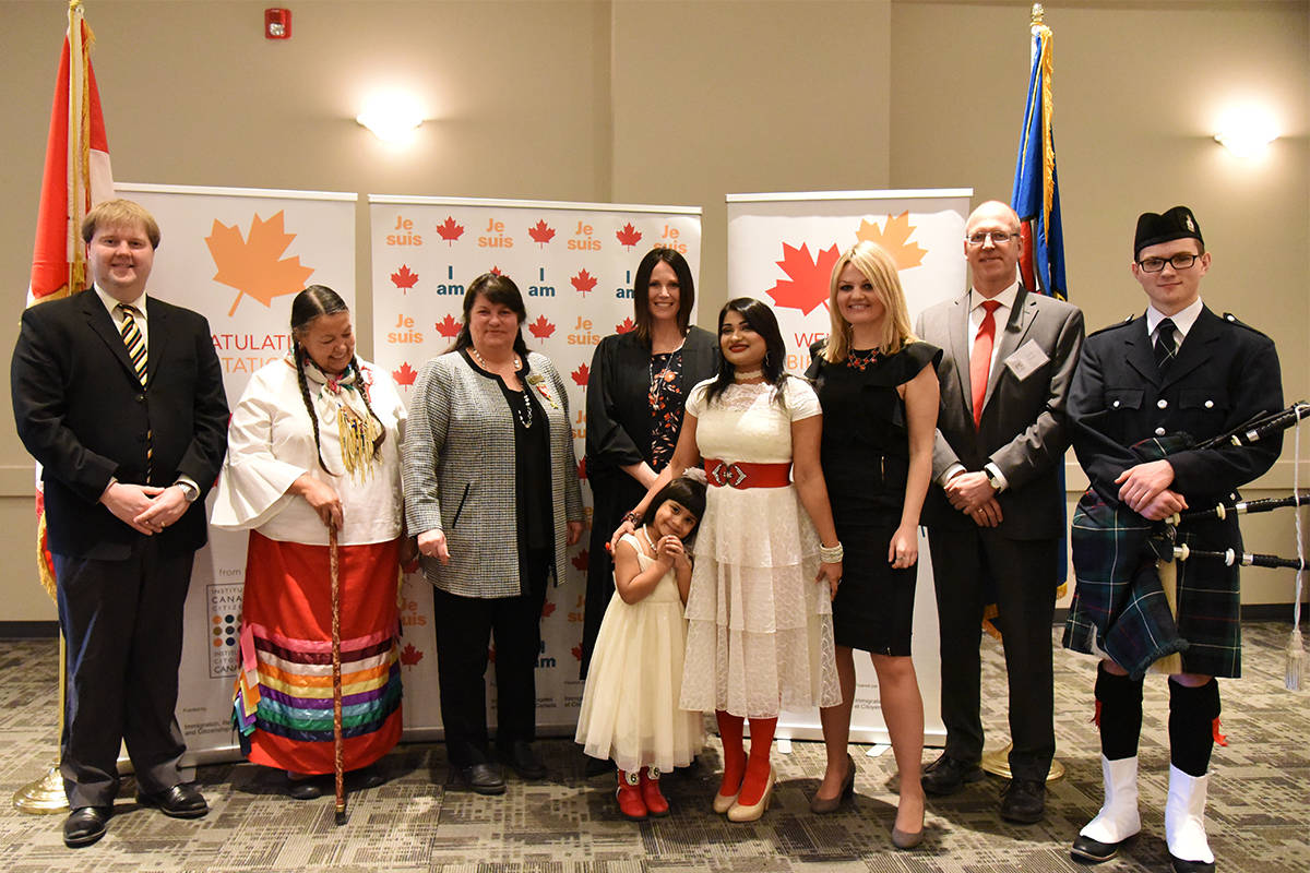 NEW CANADIAN CITIZEN - L to R: Colin Connon, assistant to MP Earl Dreeshen; Metis Cree Elder, Theresa ‘Corky’ Larsen-Jonasson; MLA Kim Schreiner, Red Deer North; Speaker Allison McLeod, citizenship supervisor for South and Central Alberta; four-year-old Afshin Noorjahan; her mother new Canadian citizen Jisana Noorjahan; Mayor Tara Veer; Frank Bauer, chair of the Red Deer volunteer committee of the ICC and the bagpiper at the Canadian citizenship ceremony at Westerner Park on March 27th.                                Michelle Falk/Red Deer Express