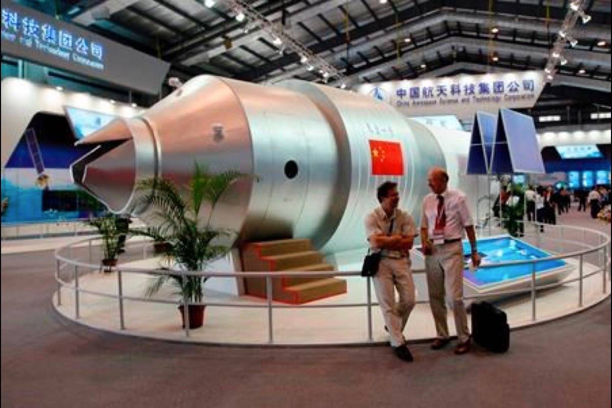 In this Nov. 16, 2010 file photo, visitors sit beside a model of China’s Tiangong-1 space station at the 8th China International Aviation and Aerospace Exhibition in Zhuhai in southern China’s Guangdong Province. (AP Photo/Kin Cheung, File)