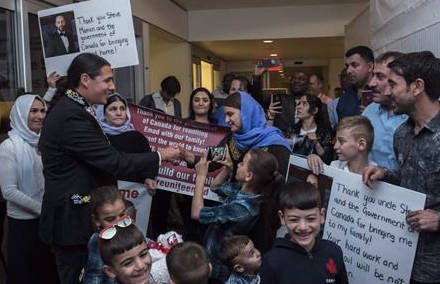 Liberal MP Robert-Falcon Ouellette, left, greets mother Nofa Mihlo Rafo as friends and family are reunited with 12-year-old Emad Mishko Tamo, third from right, in Winnipeg on August 17, 2017. (David Lipnowski/The Canadian Press)