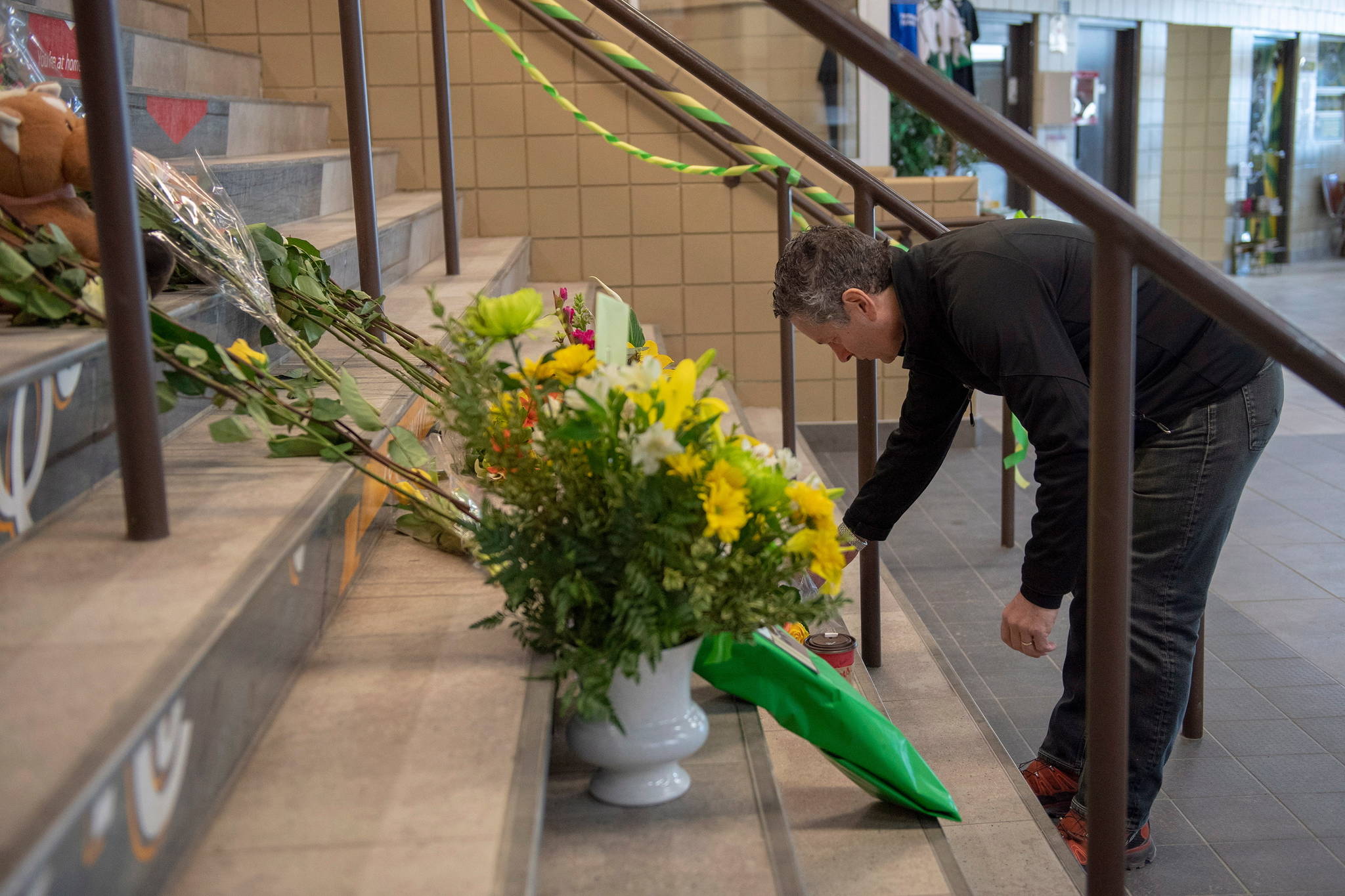 Steve Hogle, President of the Saskatoon Blades places flowers at a memorial at the stairs that lead to Elgar Petersen Arena in Humboldt, Saskatchewan, on Saturday, April 7, 2018. (Liam Richards/The Canadian Press via AP)