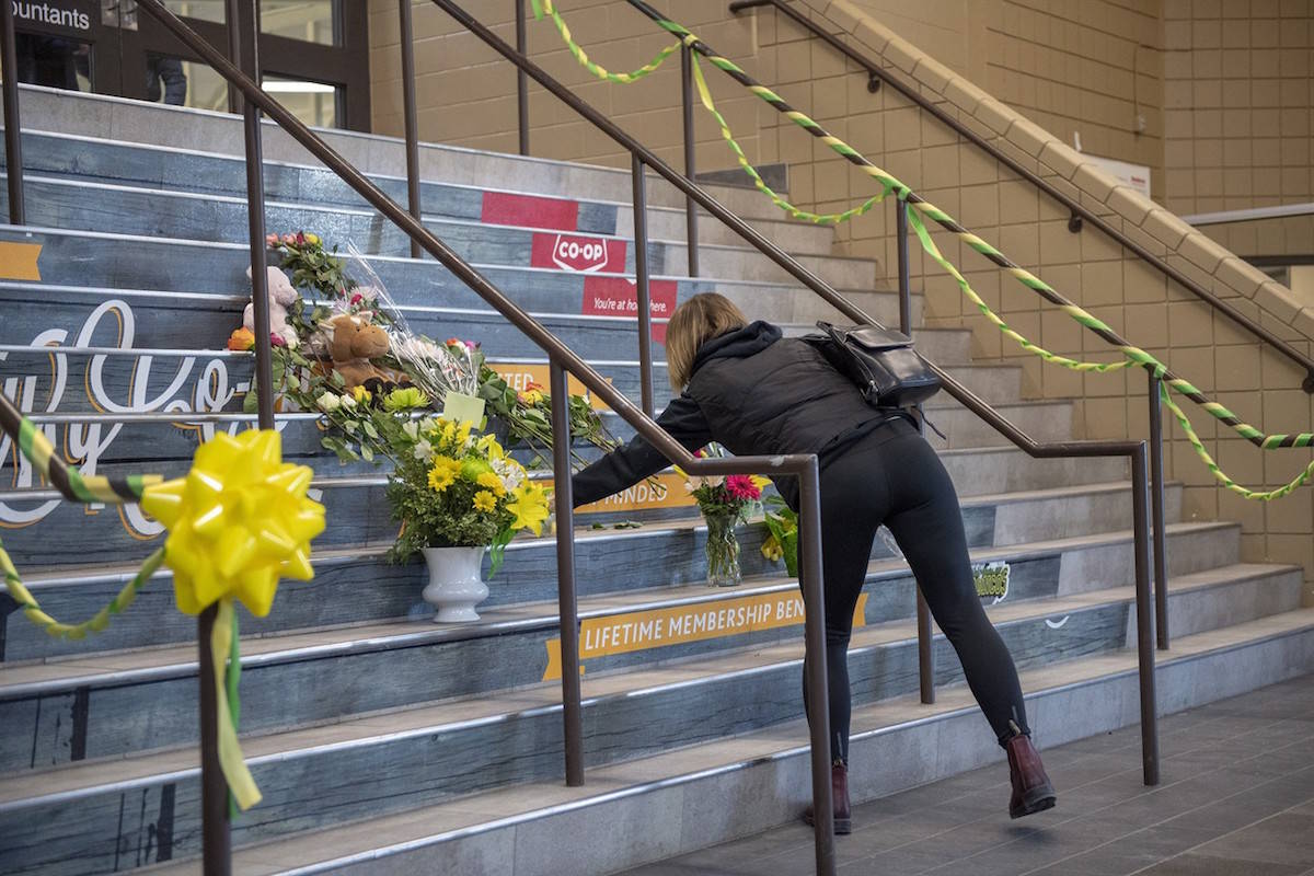A woman lays flowers at a memorial on the stairs leading into Elgar Petersen Arena, home of the Humboldt Broncos hockey team, in Humboldt, Sask., on Saturday, April 7, 2018. RCMP say 14 people are dead and 14 people were injured Friday after a truck collided with a bus carrying a junior hockey team to a playoff game in northeastern Saskatchewan. Police say there were 28 people including the driver on board the Humboldt Broncos bus when the crash occurred at around 5 p.m. on Highway 35 north of Tisdale. THE CANADIAN PRESS/Liam Richards