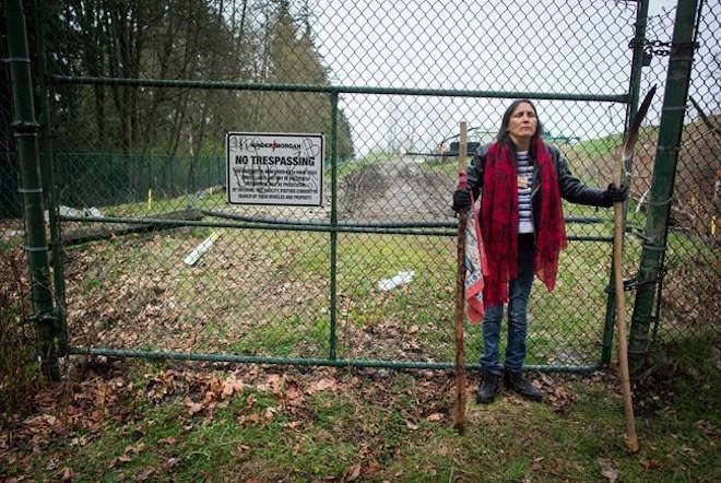 Kat Roivas, who is opposed to the expansion of the Kinder Morgan Trans Mountain pipeline, stands at an access gate at the company’s property near an area where work is taking place, in Burnaby, B.C., on Monday April 9, 2018. THE CANADIAN PRESS/Darryl Dyck
