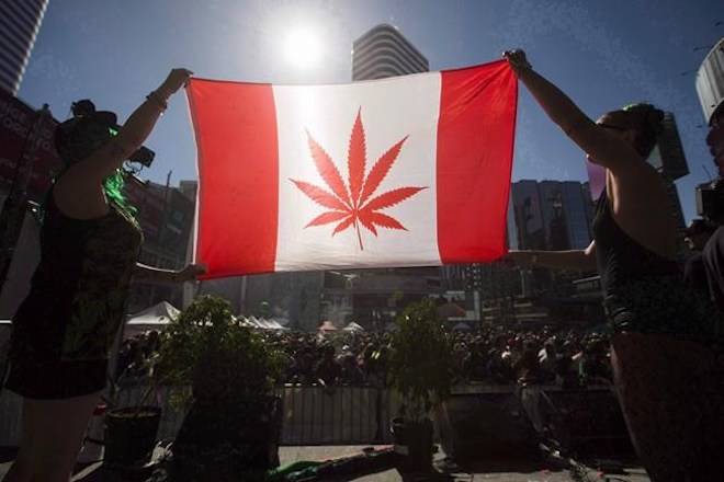 Two people hold a modified design of the Canadian flag with a marijuana leaf in in place of the maple leaf during the “4-20 Toronto” rally in Toronto, April 20, 2016. Cannabis activists say although this year’s 4-20 celebrations across the country will likely be the last before recreational pot use becomes legal, there’s still a lot to fight for. THE CANADIAN PRESS/Mark Blinch