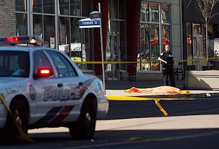 A police officer stands over a covered body in Toronto after a van mounted a sidewalk crashing into a number of pedestrians on Monday, April 23, 2018. THE CANADIAN PRESS/Nathan Denette