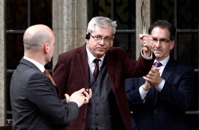 NDP MP Charlie Angus holds a feather as he rises to vote in favour of the NDP’s motion calling on the House of Commons to officially ask the Pope to apologize to residential school survivors, on Parliament Hill in Ottawa on Tuesday, May 1, 2018. (Justin Tang/The Canadian Press)
