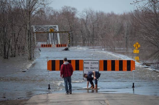 Residents move the barricade out of the rising floodwater from the Saint John River in Lakeville Corner, N.B. on Wednesday, May 2, 2018. THE CANADIAN PRESS/Darren Calabrese