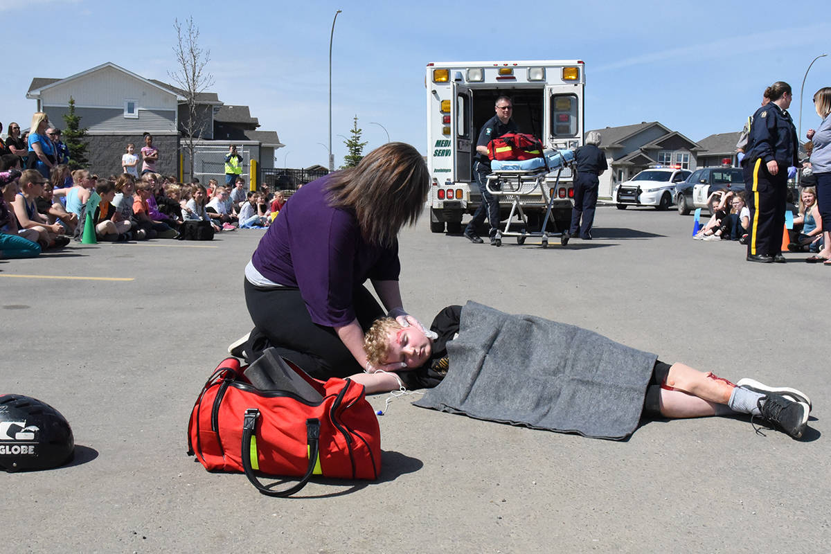 SAFETY FIRST - Braiden Drobot, nine-years-old, and his mom Cheryl Drobot act out a mock incident for Occupational Safety and Health Week in the parking lot of Iron Ridge Intermediate School.                                Michelle Falk/Red Deer Express