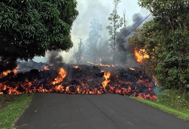 In this Sunday, May 6, 2018 photo provided by the U.S. Geological Survey, a lava flow moves across Makamae Street in the Leilani Estates subdivision near Pahoa on the island of Hawaii. Kilauea volcano has destroyed more than two dozen homes since it began spewing lava hundreds of feet into the air last week, and residents who evacuated don’t know how long they might be displaced. The decimated homes were in the Leilani Estates subdivision, where molten rock, toxic gas and steam have been bursting through openings in the ground created by the volcano. (U.S. Geological Survey via AP)
