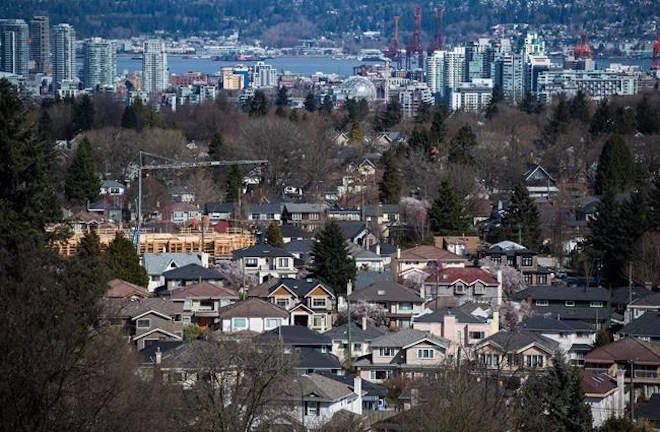 A condo building is seen under construction surrounded by houses as condo towers are seen in the distance in Vancouver, B.C., on Friday March 30, 2018. THE CANADIAN PRESS/Darryl Dyck