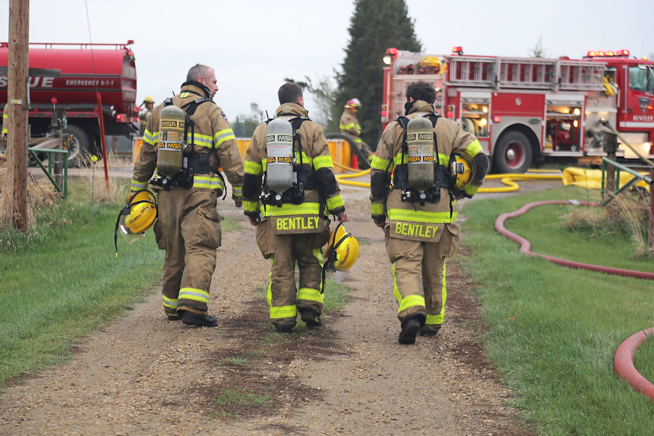 Assisting others: The Bentley District Fire Department firefighters walk back to their pumper trucks after the structure fire. It’s unknown the cause of the fire but several dogs and puppies were rescued. Photo courtesy of Kathi Issler, Bentley District Fire Department