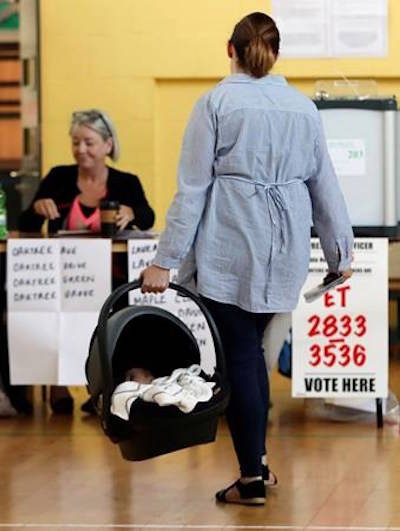 A woman carries a baby in a cot as goes to cast her vote at a polling station in the referendum on the 8th Amendment of the Irish Constitution, in Dublin, Friday, May 25, 2018. (Niall Carson/PA via AP)