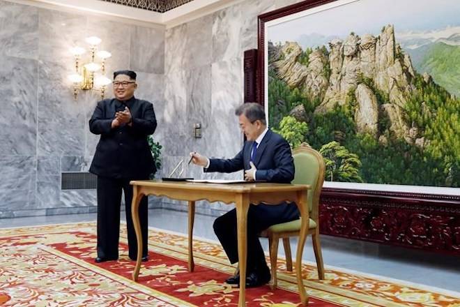 In this May 26, 2018 photo provided on May 27, 2018, by South Korea Presidential Blue House, South Korean President Moon Jae-in writes on a visitor’s book as North Korean leader Kim Jong Un, left, stands at the northern side of Panmunjom in North Korea. (South Korea Presidential Blue House via AP)