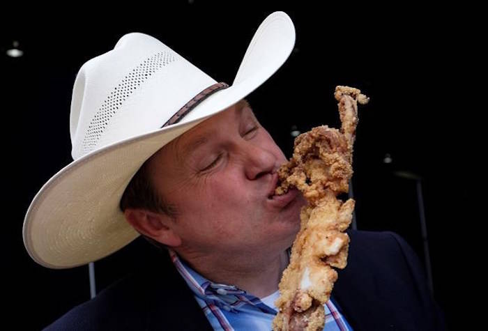James Radke, midway operations manager at the Calgary Stampede, samples a deep fried giant squid that will be available at this year’s Stampede in Calgary, Tuesday, June 5, 2018. THE CANADIAN PRESS/Jeff McIntosh