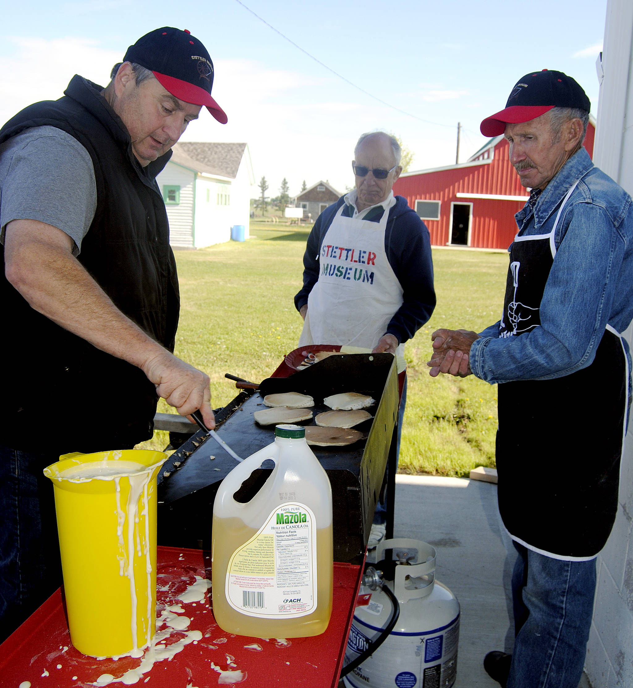 Murray Wahlund, left, Gilbert Ellis, middle, and Wilf Buehler flip pancakes during Stettler Town and Country Museum’s pancake breakfast June 2. (Lisa Joy/Stettler Independent)
