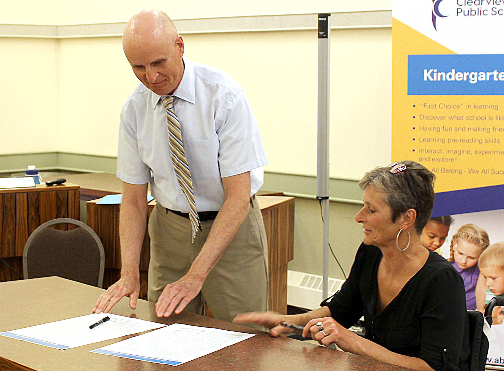 Clearview Public Schools Board Chairperson Ken Checkel and Wolf Creek Public Schools Board Chairperson Lorrie Jess sign the High School Success Initiative Agreement between the two school boards in the Clearview offices on June 20. (Kevin Sabo photo)