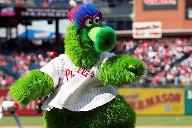 In this April 5, 2018 photo, The Phillie Phanatic reacts prior to the first inning of a baseball game against the Miami Marlins in Philadelphia. Kathy McVay says she was at Monday, June 18, Phillies game when the team‚Äôs mascot, the Phillie Phanatic, rolled out his hot dog launcher. McVay was sitting near home plate and all of a sudden she says a hot dog wrapped in duct tape struck her in the face. She left the game to get checked out at a hospital, and she says she has a small hematoma. The Phillies apologized to McVay Tuesday and the team has offered her tickets to any game. (AP Photo/Chris Szagola)