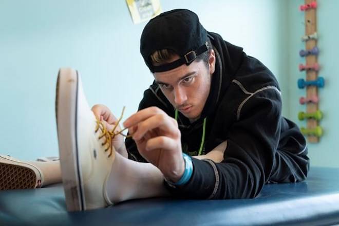 Humboldt Broncos survivor Ryan Straschnitzki concentrates as he ties his shoe during a physiotherapy session at the Shriners Hospital in Philadelphia on Tuesday, June 26, 2018. THE CANADIAN PRESS/Paul Chiasson