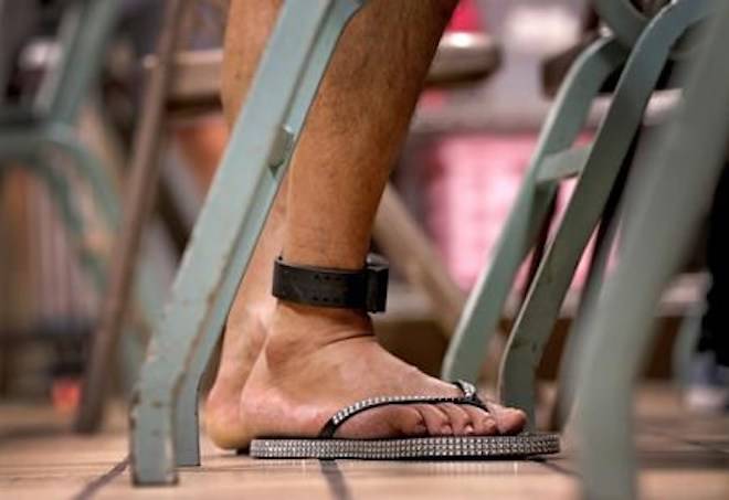 A migrant parent wears an ankle monitor bracelet above his donated flip-flops at the Annunciation House, Tuesday, June 26, 2018, in El Paso, Texas. (AP Photo/Matt York)