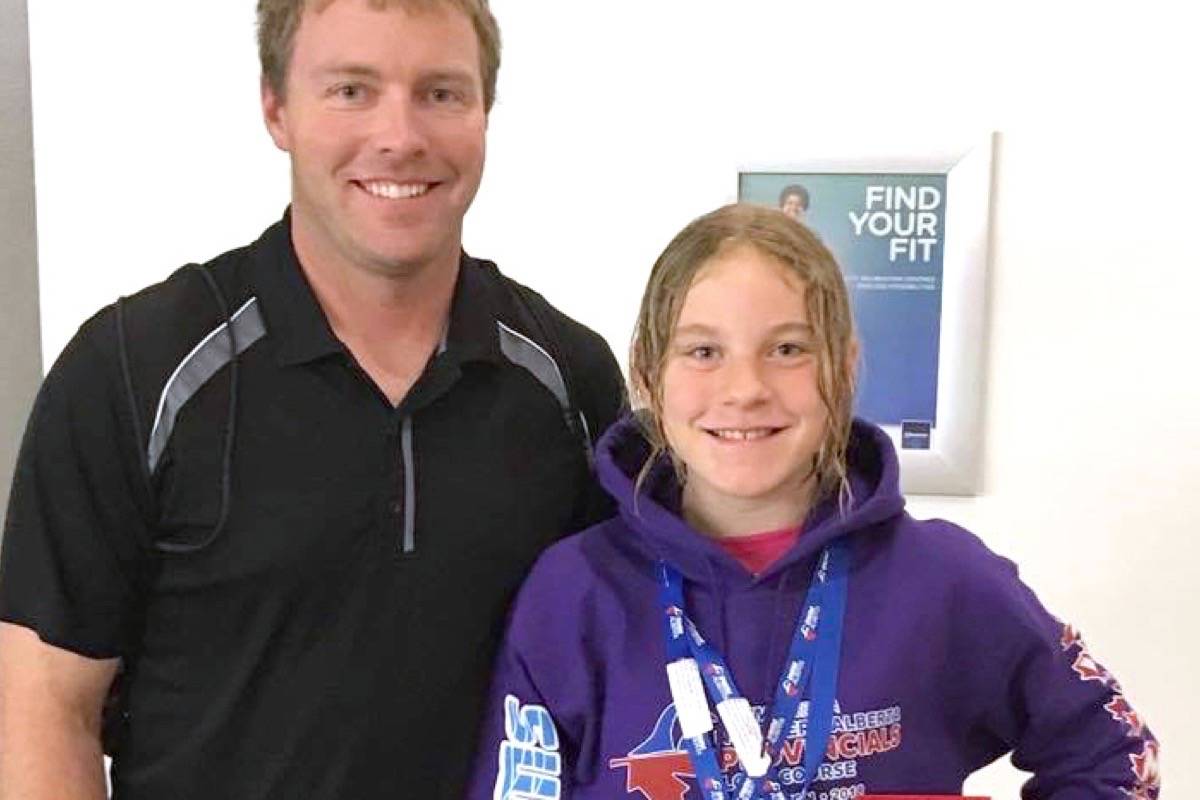 Stettler’s Elizabeth Morton, 10, wins gold at the Northern Alberta Long Course Swimming Provincials in Edmonton. With her is swim coach Mark Way. (Contributed photo)