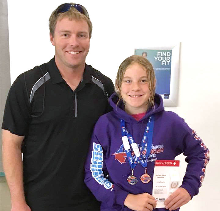 Stettler’s Elizabeth Morton, 10, wins gold at the Northern Alberta Long Course Swimming Provincials in Edmonton. With her is swim coach Mark Way. (Contributed photo)