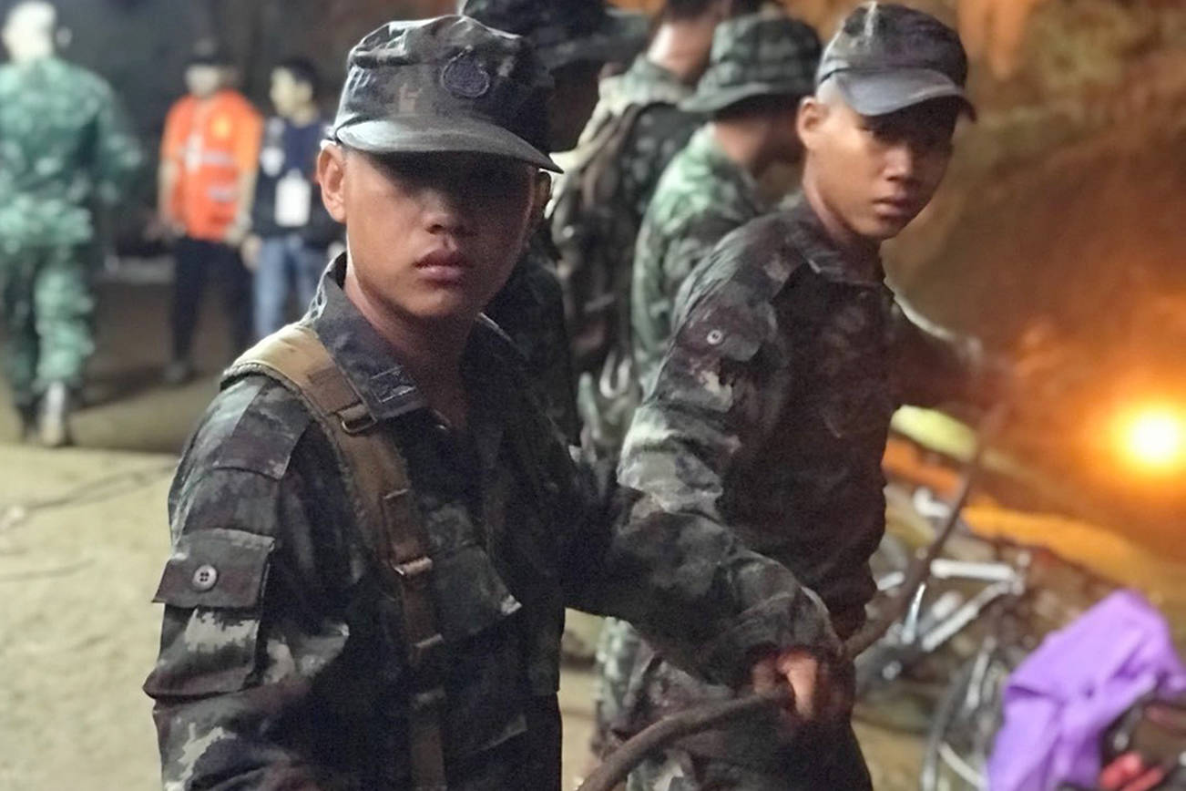 Soldiers guide auxiliary power lines into a cave where the main staging area is to continue the search for a group of missing boys and their coach, Tuesday, June 26, 2018, in Mae Sai, Chiang Rai province, northern Thailand. (Tassanee Vejpongsa/AP)