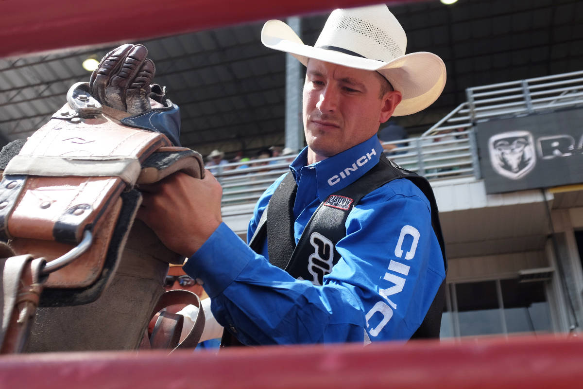 Bareback rider Jake Vold prepares his saddle before the bareback riding event.