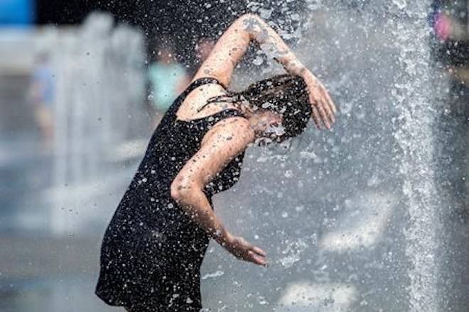 A woman cools down in a water fountain as she beats the heat in Montreal, Monday, July 2, 2018. THE CANADIAN PRESS/Graham Hughes