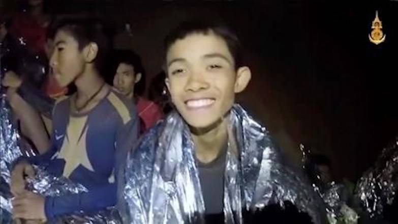 In this July 3, 2018, image taken from video provided by the Royal Thai Navy Facebook Page, a Thai boy smiles as Thai Navy SEAL medic help injured children inside a cave in Mae Sai, northern Thailand. (Royal Thai Navy Facebook Page via AP)