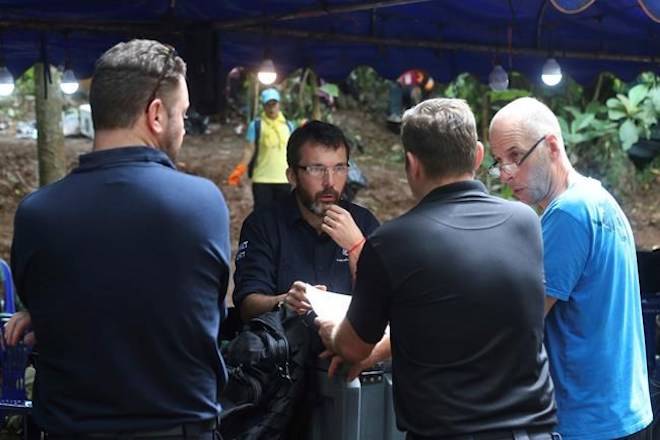 Australian Federal Police and Defense Force personnel talk each other near a cave where 12 boys and their soccer coach are trapped, in Mae Sai, Chiang Rai province, in northern Thailand, Thursday, July 5, 2018. With more rain coming, Thai rescuers are racing against time to pump out water from a flooded cave before they can extract 12 boys and their soccer coach with minimum risk, officials said Thursday. (AP Photo/Sakchai Lalit)