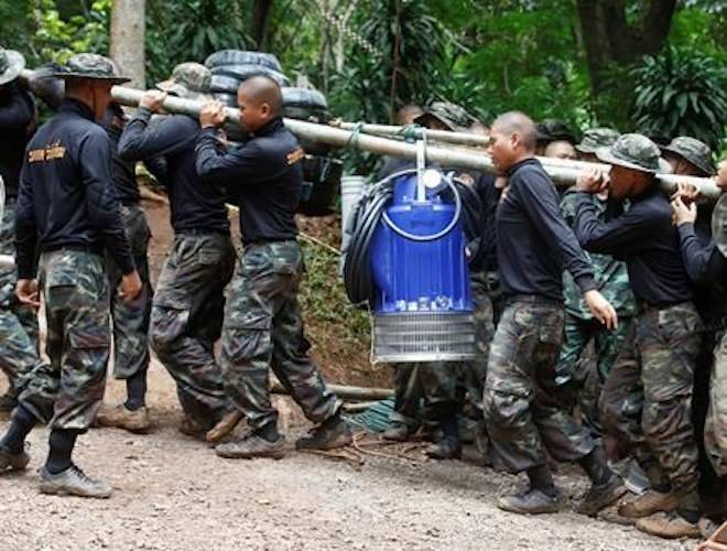 Soldiers carry a pump to help drain the rising flood water in a cave where 12 boys and their soccer coach have been trapped since June 23, in Mae Sai, Chiang Rai province, in northern Thailand Friday, July 6, 2018. (AP Photo/Sakchai Lalit)