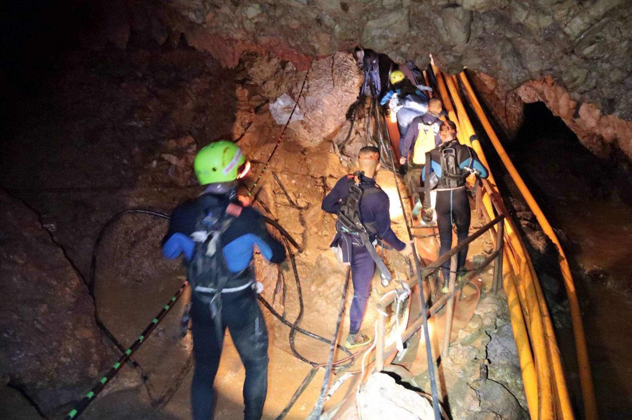 In this undated photo released by Royal Thai Navy on Saturday, July 7, 2018, Thai rescue team members walk inside a cave where 12 boys and their soccer coach were trapped since June 23, in Mae Sai, Chiang Rai province, northern Thailand. (Royal Thai Navy via AP)