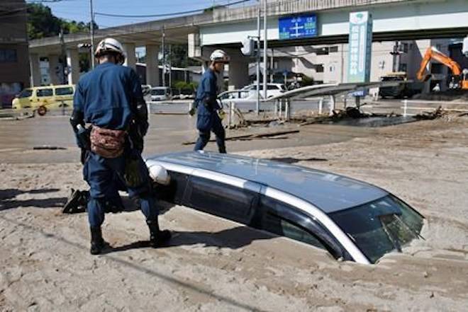 A police officer looks into a car buried in mud during a search operation in the aftermath of heavy rains in Kure, Hiroshima prefecture, southwestern Japan, Wednesday, July 11, 2018. Rescuers were combing through mud-covered hillsides and along riverbanks Tuesday searching for dozens of people missing after heavy rains unleashed flooding and mudslides in southwestern Japan. (Shingo Nishizume/Kyodo News via AP)