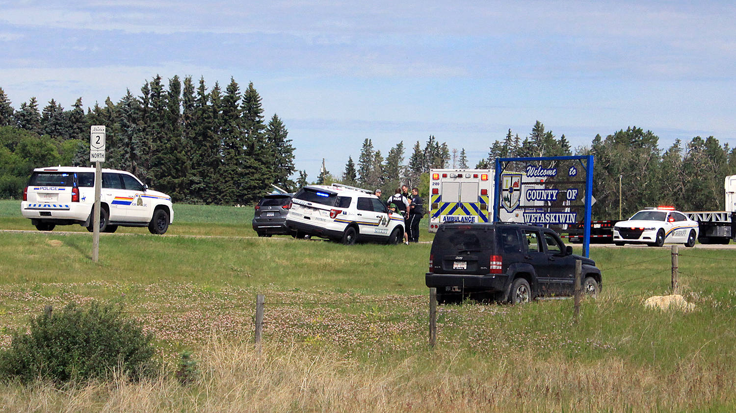 Members of the Ponoka Integrated Traffic Unit speak to witnesses at the scene of a strange incident July 12 just north of Secondary Highway 611 on Highway 2. A woman drove her vehicle into the ditch and then ran onto the highway, narrowly escaping being run over. Photo by Jordie Dwyer