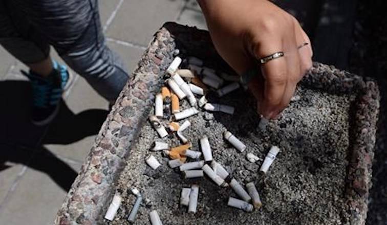 A smoker puts out a cigarette in a public ash tray in Ottawa on Tuesday, May 31, 2016. THE CANADIAN PRESS/Sean Kilpatrick