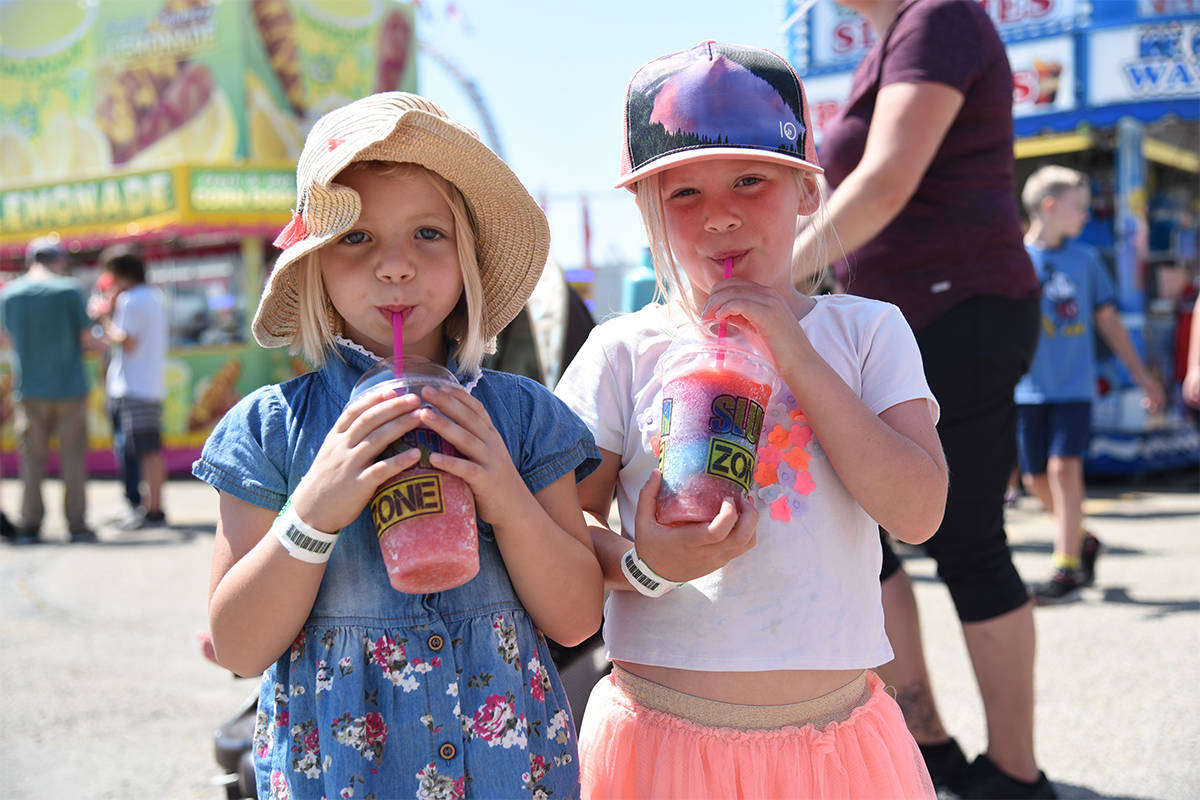 COOLING OFF - Six-year-old Madisyn Woolward and her friend Lilly Strauss enjoy some refreshing drinks from the Slush Zone in the Grub Hub at Westerner Days.                                Michelle Falk/Red Deer Express