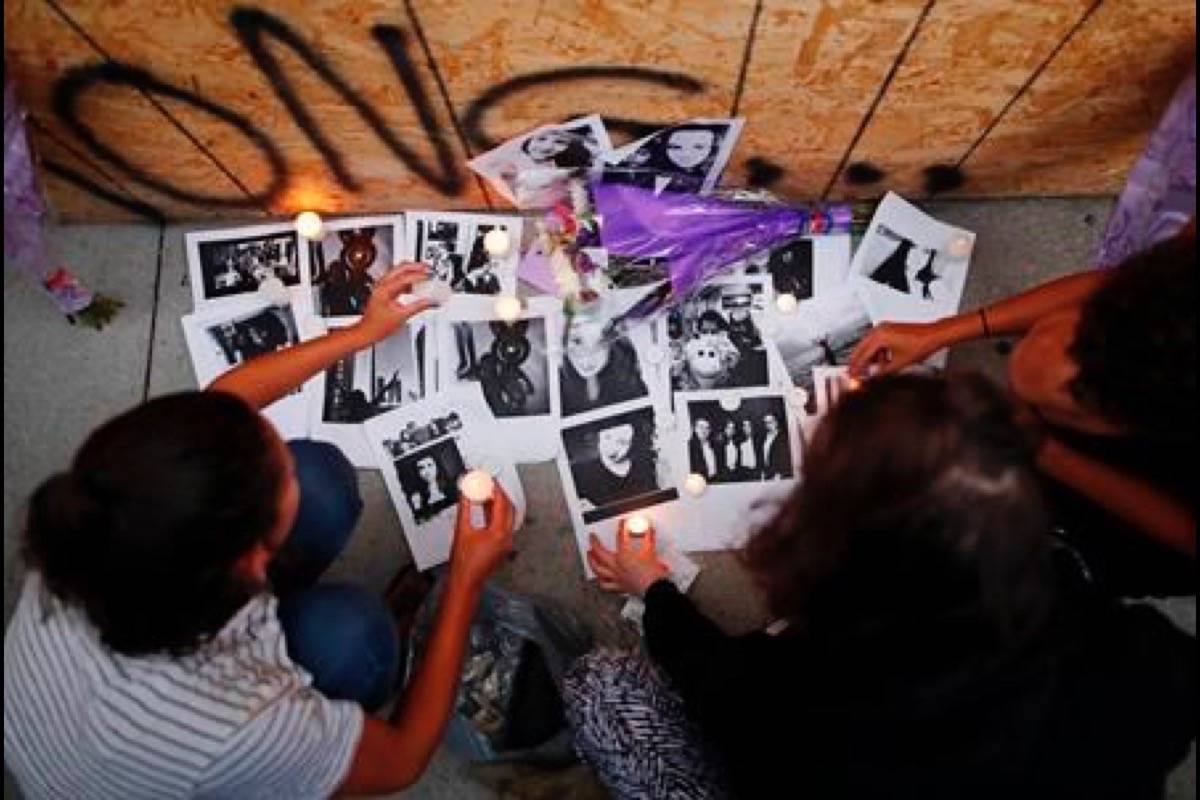 People light candles and leave photos of 18-year-old victim Reese Fallon at a memorial remembering the victims of a shooting on Sunday evening on Danforth, Ave. in Toronto on Monday, July 23, 2018. (Mark Blinch/The Canadian Press)