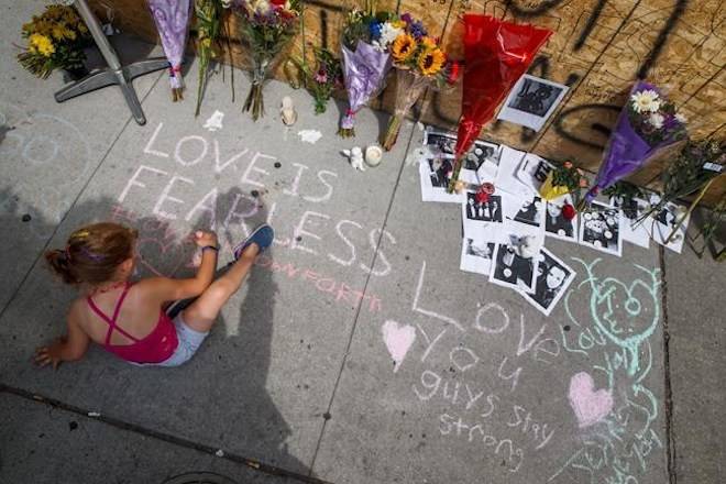 A young girl writes a message on the sidewalk at a site remembering the victims of a shooting on Sunday evening on Danforth Avenue, in Toronto on Monday, July 24, 2018. THE CANADIAN PRESS/Mark Blinch