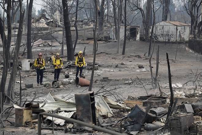San Bernardino County Fire Department firefighters assess the damage to a neighborhood in the aftermath of a wildfire, Sunday, July 29, 2018, in Keswick, Calif. (AP Photo/Marcio Jose Sanchez)