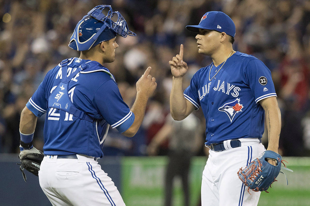 Toronto Blue Jays closer Roberto Osuna and catcher Luke Maile celebrate their American League MLB baseball win over the New York Yankees, in Toronto on Saturday, March 31, 2018. THE CANADIAN PRESS/Fred Thornhill