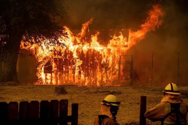 Firefighters monitor a burning outbuilding to ensure flames don’t spread as the River Fire burns in Lakeport, Calif., on Monday, July 30, 2018. (AP Photo/Noah Berger)