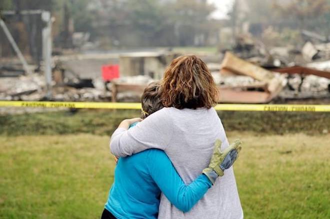 Carol Smith, left, gets a hug from her daughter Suzie Scatena, after seeing her fire-ravaged home for the first time Thursday, Aug. 2, 2018, in Redding, Calif. (AP Photo/Marcio Jose Sanchez)