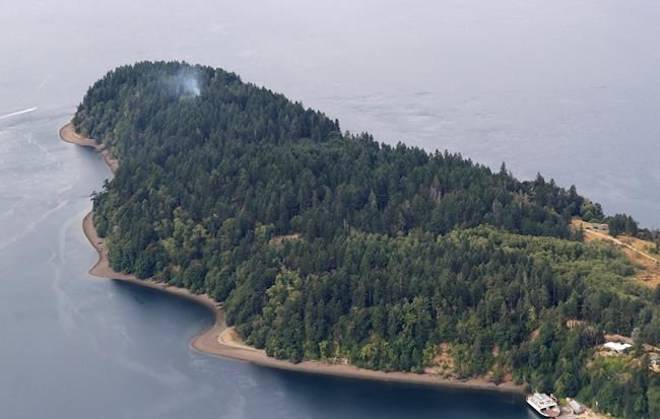 Smoke rises from the site on Ketron Island in Washington state where an Horizon Air turboprop plane crashed Friday after it was stolen from Sea-Tac International Airport as seen from the air, Saturday, Aug. 11, 2018, near Steilacoom, Wash. (AP Photo/Ted S. Warren)